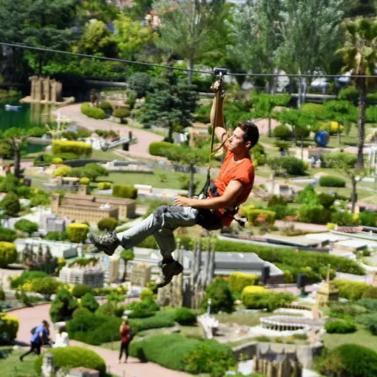 man using a zip line across a green natural landscape
